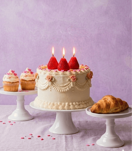 Decorative birthday cake with lit candles on a purple background